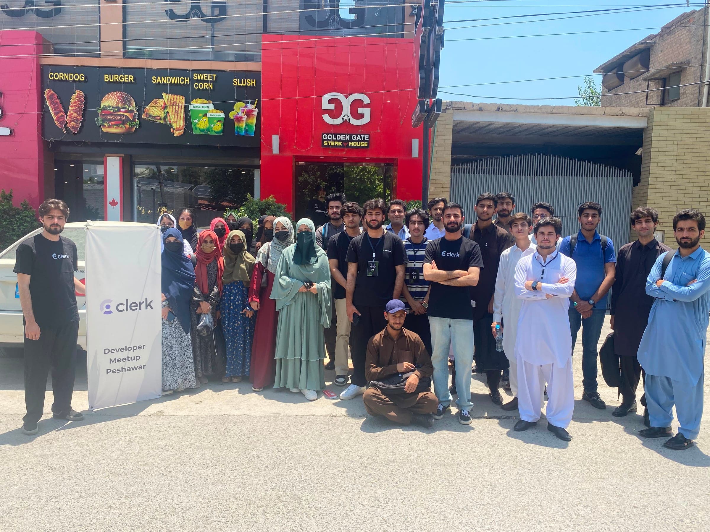 Group photo outside a storefront with a Clerk banner